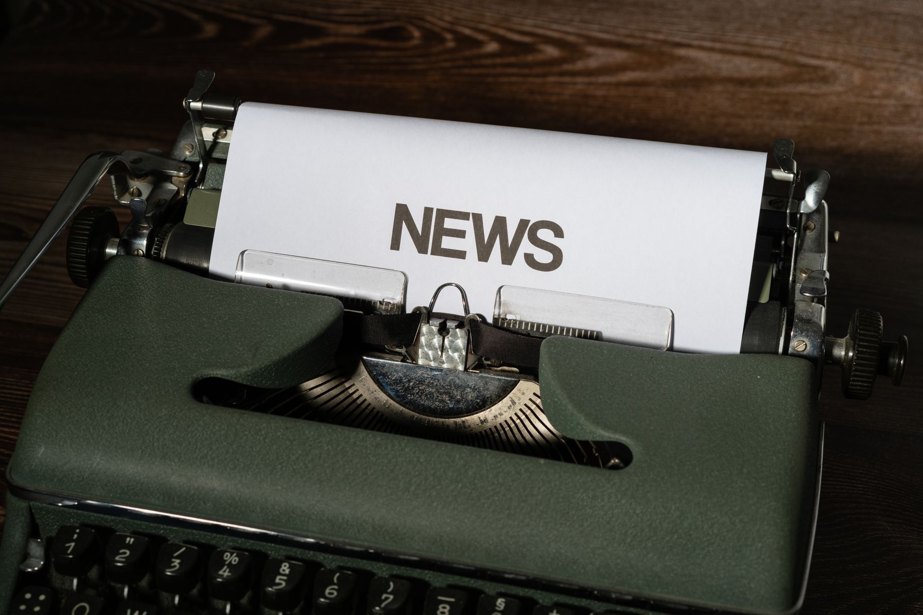 A retro typewriter featuring a 'NEWS' headline typed on white paper against a wooden surface. — LiraSpin Casino: Szybkie Wygr