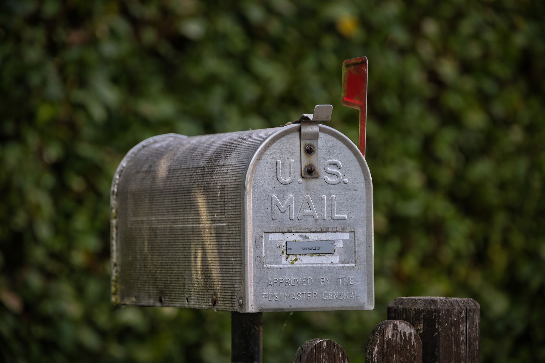A traditional U.S. mailbox with red flag against a lush green blurred background. — Prachtige_kansen_en_luckygem_voor_elke_sp
