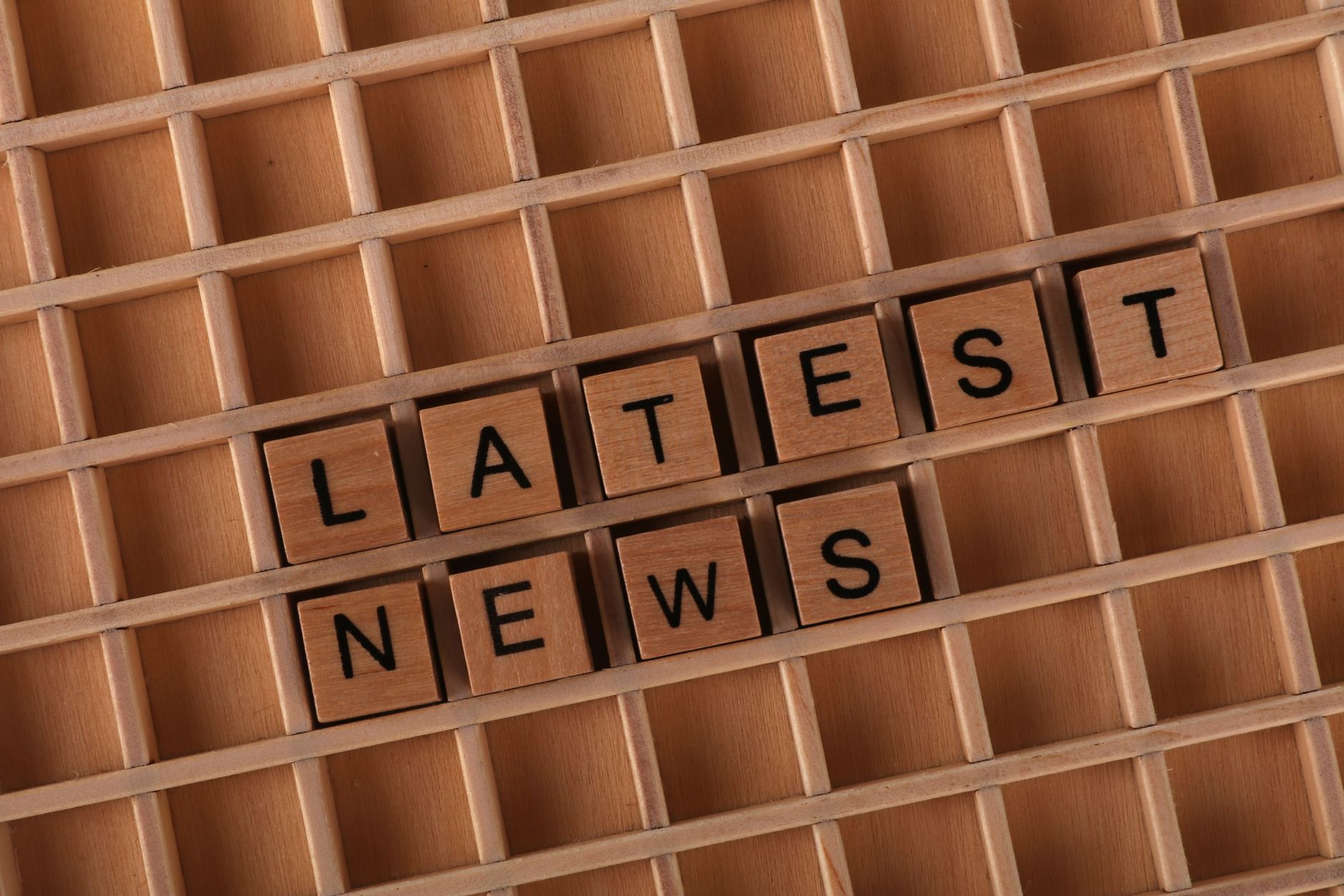 Wooden letter blocks spelling 'Latest News' on a grid surface. Ideal for media concepts. — Tiki Casino: Was sagen die Experte