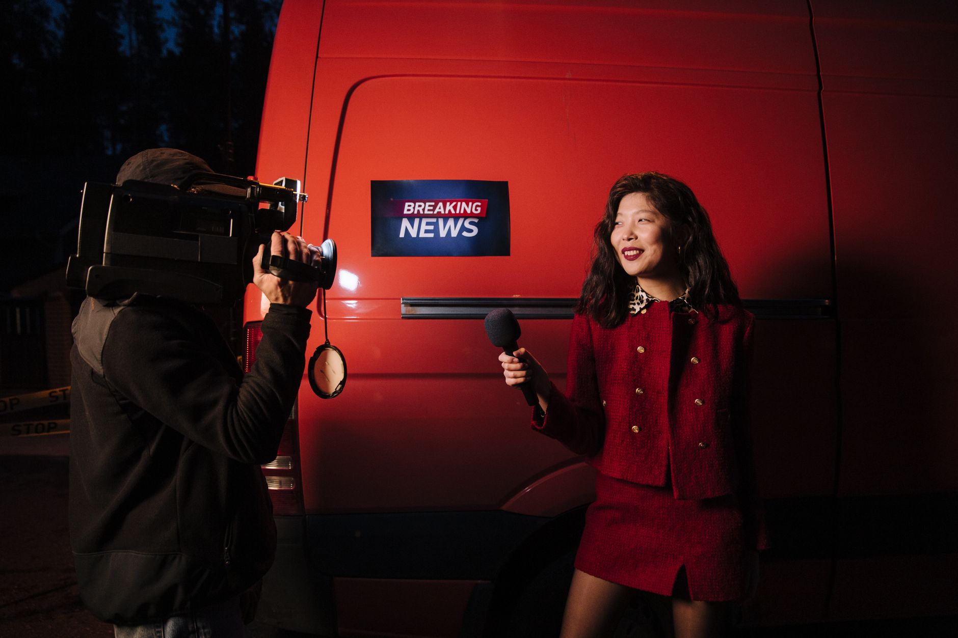 Dynamic news reporter holding microphone near red van during nighttime outdoor broadcast. — Warum Spieler Polestar Casino tre
