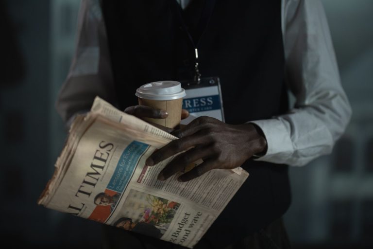 Close-up of a journalist holding a newspaper and coffee cup, conveying press and media concept. — Welches Bonusprogramm biete