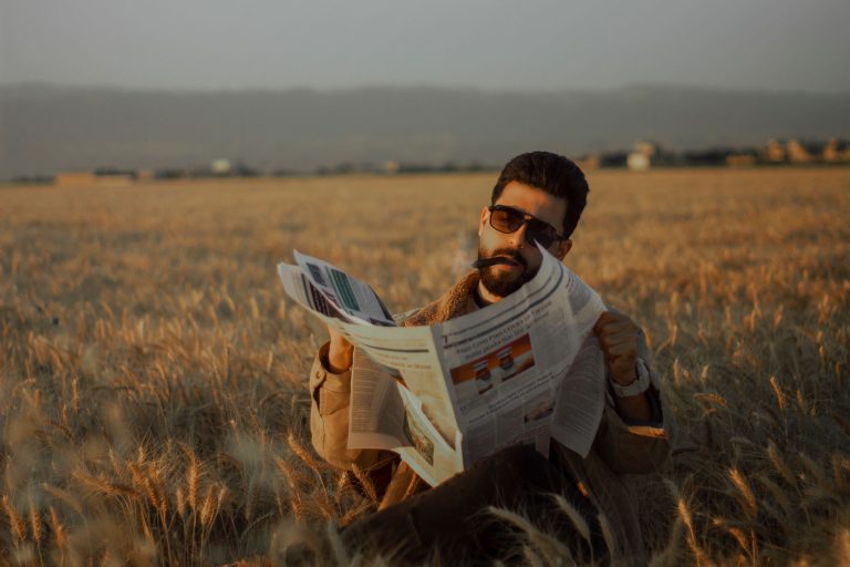 Middle-aged man sitting in a serene wheat field, reading a newspaper during the day. — Wie geht es am besten zum Jackpot im S